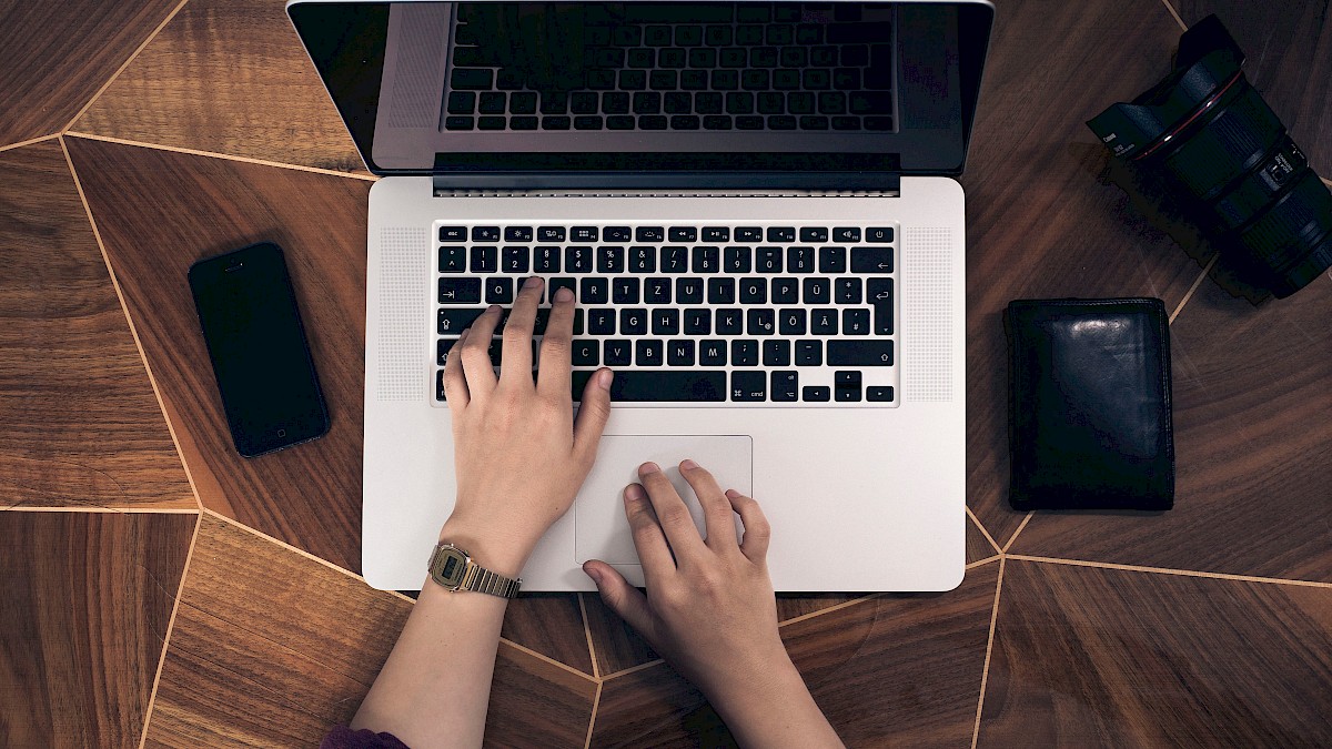 Zwei Hände auf tastatur und Mousepad eines geöffneten Notebooks. Von oben fotografiert.